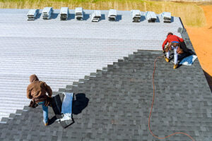 Roofers nailing down asphalt roofing